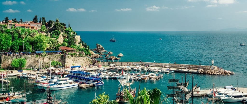 Vista do porto de Antália com o mar ao fundo e barcos ancorados ao longo do cais