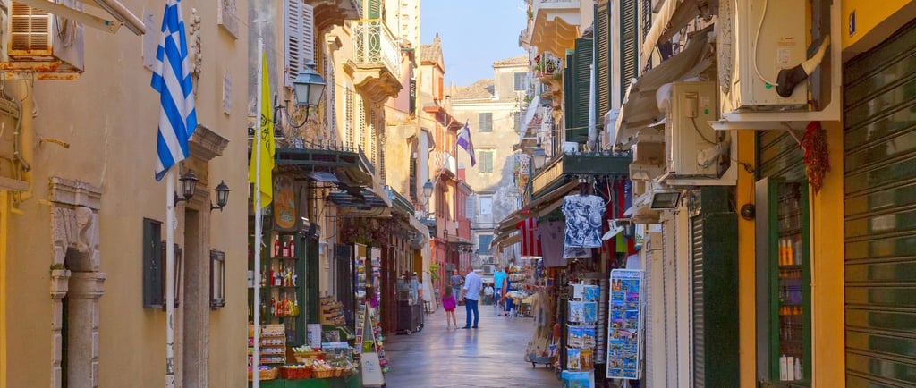 Centro histórico de Corfu com lojas abertas e movimento típico de dias com navios atracados.