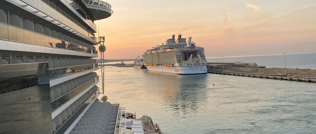 Navios de cruzeiro ancorados em porto italiano, com paisagem costeira ao fundo.