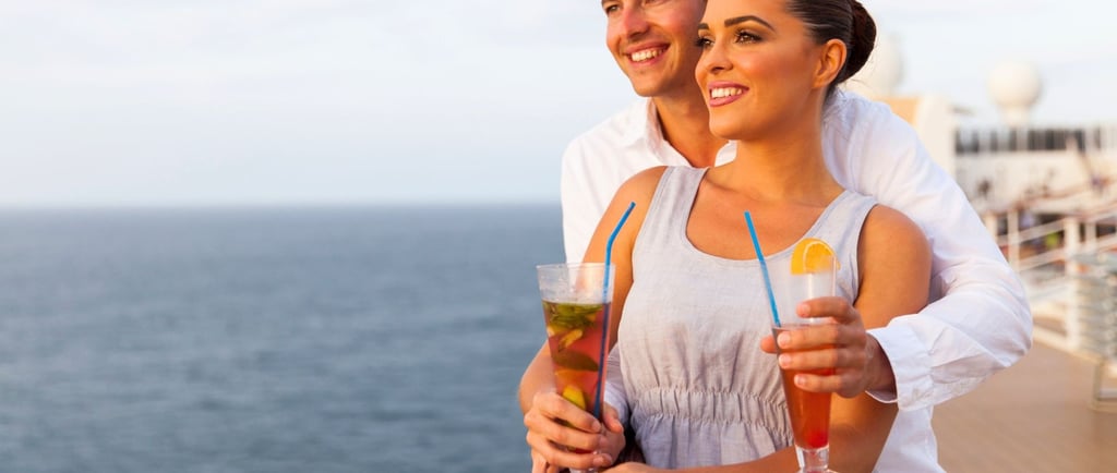 Casal apreciando drinks no deck do navio com vista para o mar, representando pacote individual e consumo por pessoa
