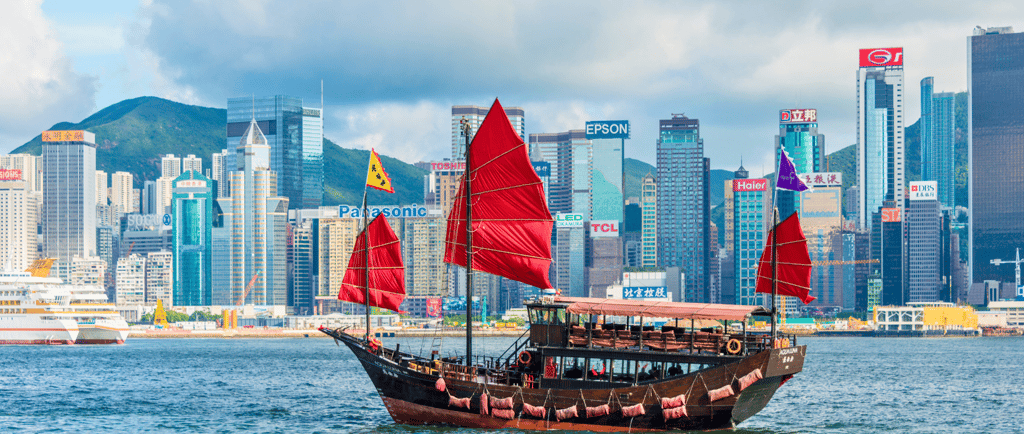 Barco de passeio navegando pela baía de Hong Kong em um dia ensolarado.