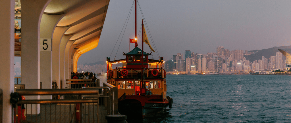 Pier de embarque do ferry em Hong Kong com passageiros prontos para passeio pela baía.