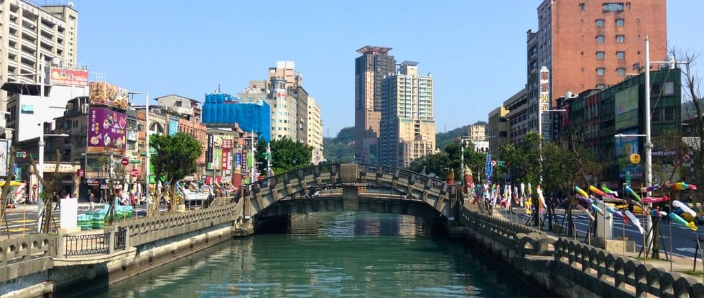 Canal de Keelung com a cidade ao redor, visto do porto, mostrando barcos e áreas urbanas costeiras..