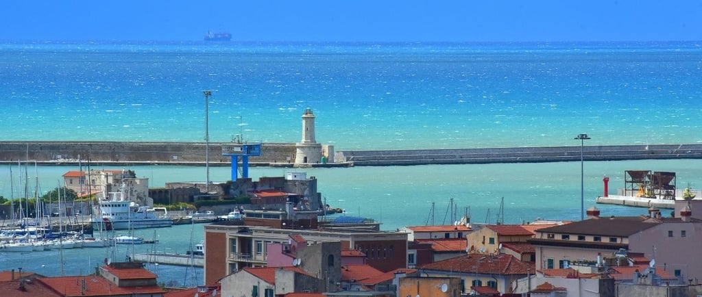 Vista do porto de Livorno com o farol e o mar azul ao fundo.