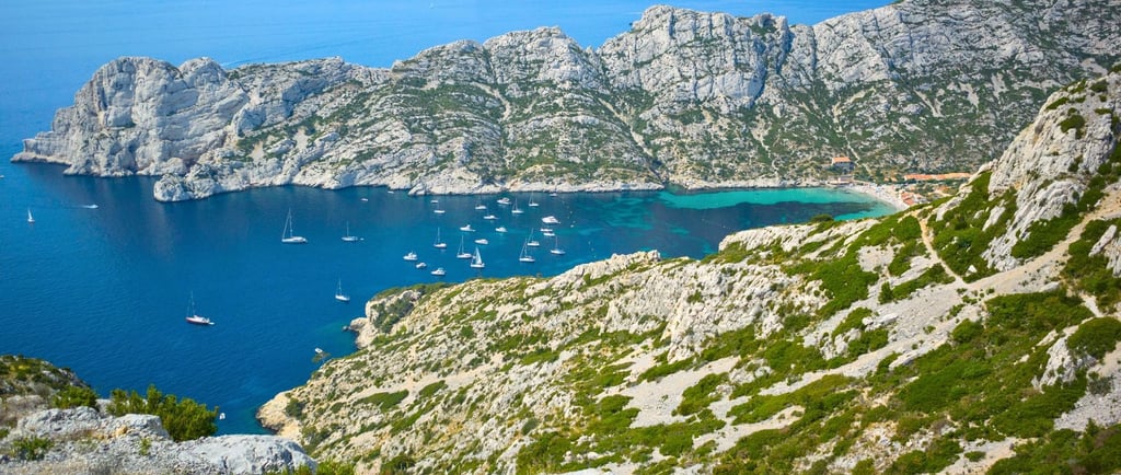 Vista panorâmica das Calanques de Marselha com o mar azul ao fundo, observada do topo da colina.