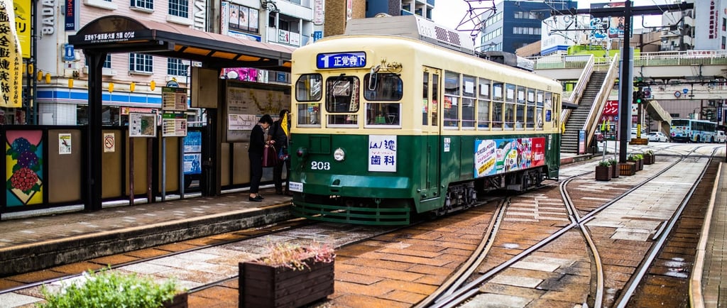 Tram elétrico de Nagasaki parado na estação, pronto para transportar passageiros pelo centro histórico.