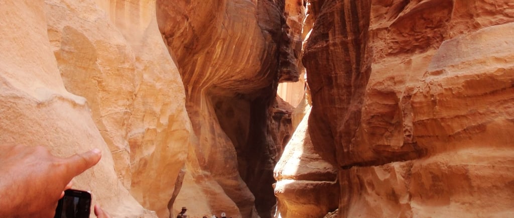 Grupo de turistas descendo pelo Siq em Petra, com as imponentes paredes rochosas à medida que o cami