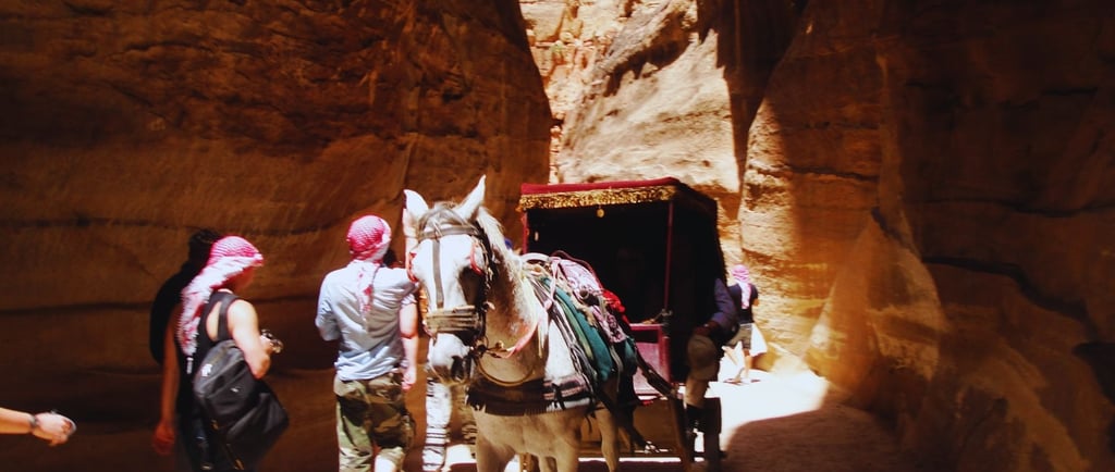 Descida do Siq em Petra com vista de burro e carruagem seguindo pelo caminho estreito.