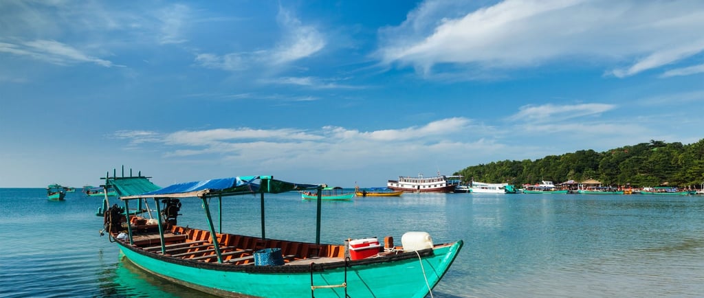 Barco de passeio ancorado na areia em Sihanoukville, pronto para levar visitantes às ilhas próximas.