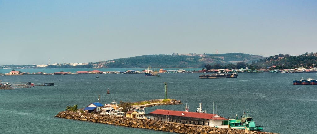 Chegada ao porto de Sihanoukville vista do navio, com barcos ancorados e a cidade ao fundo.