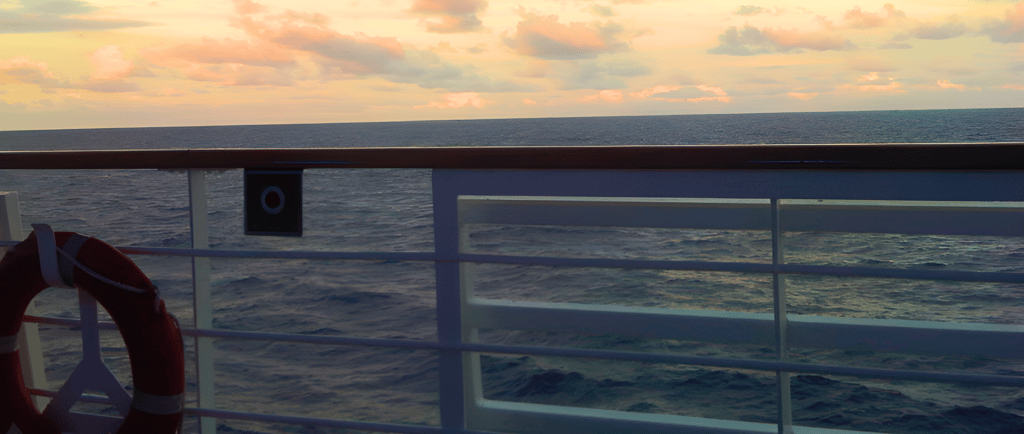 Vista do deck de navio de cruzeiro no mar ao entardecer rumo à Europa.