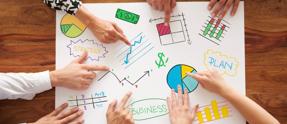 a group of people sitting around a table with a paper board with a diagram of