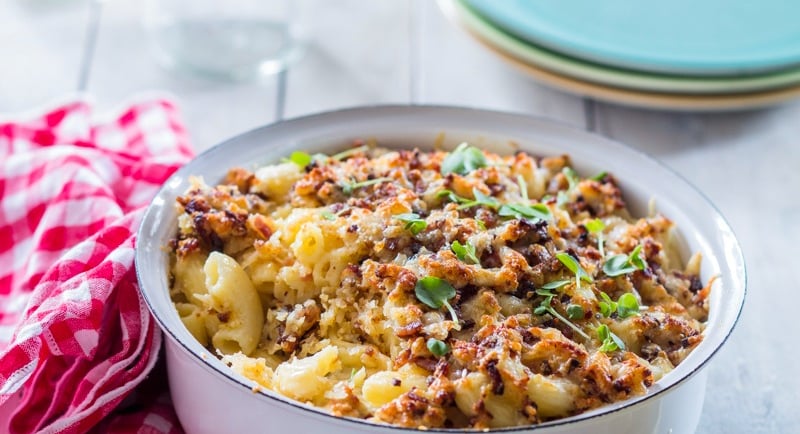 Mac and Cheese in a tin bowl with a crunchy topping and a checked napkin to the side