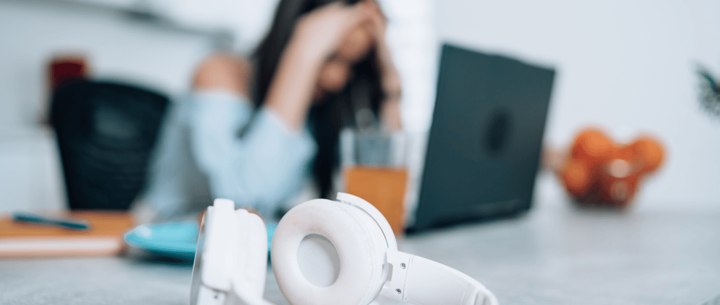 a woman sitting at a table with a laptop and headphones