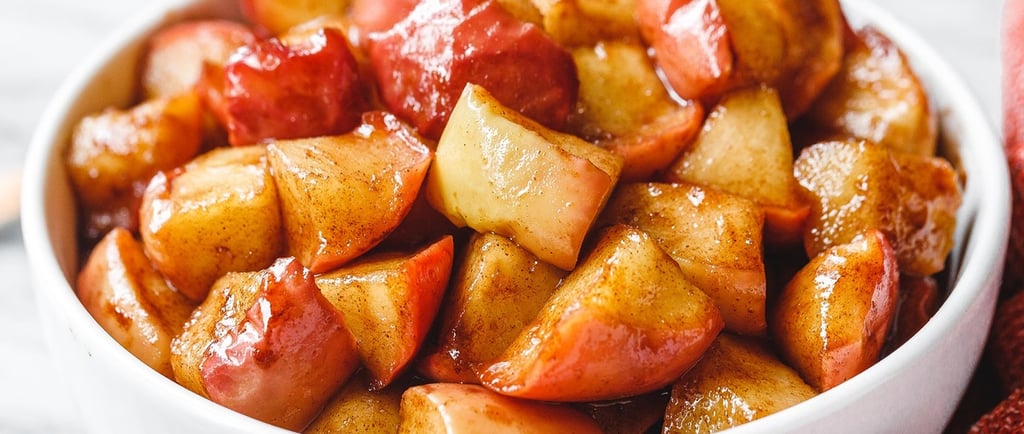 A white bowl filled with warm, glazed cinnamon fried apples, a perfect autumn dessert or side dish.