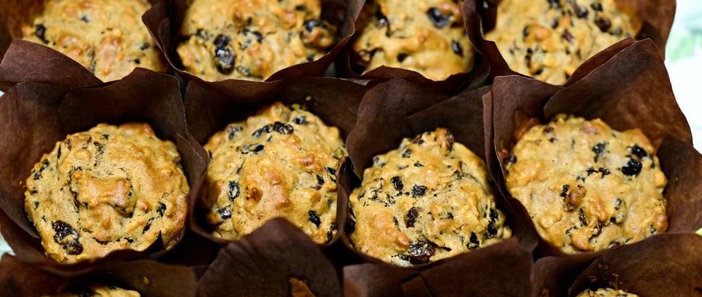 Freshly baked homemade banana nut muffins with dark raisins in brown paper liners.