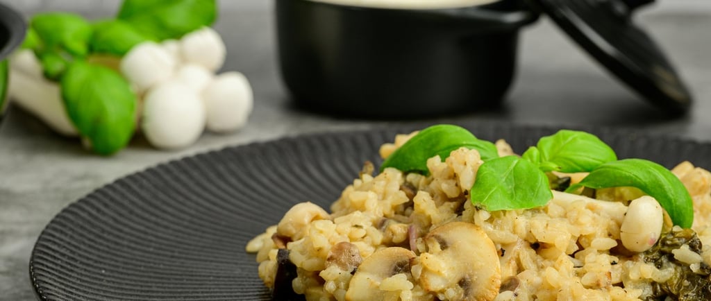 Creamy mushroom risotto with fresh basil leaves served on a textured black plate.