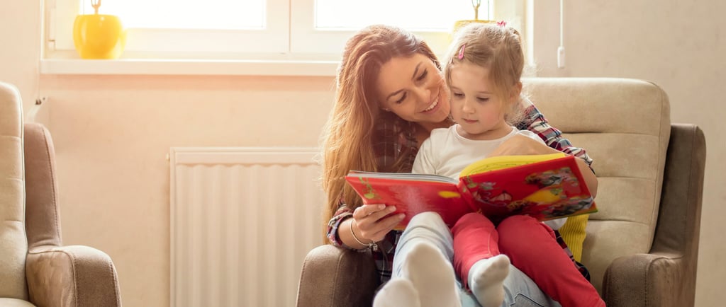 a woman sitting in a chair with a child and teaching reading
