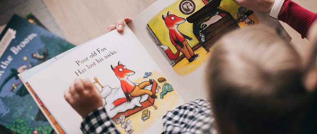 a child's hands are holding a book, the child is learning reading