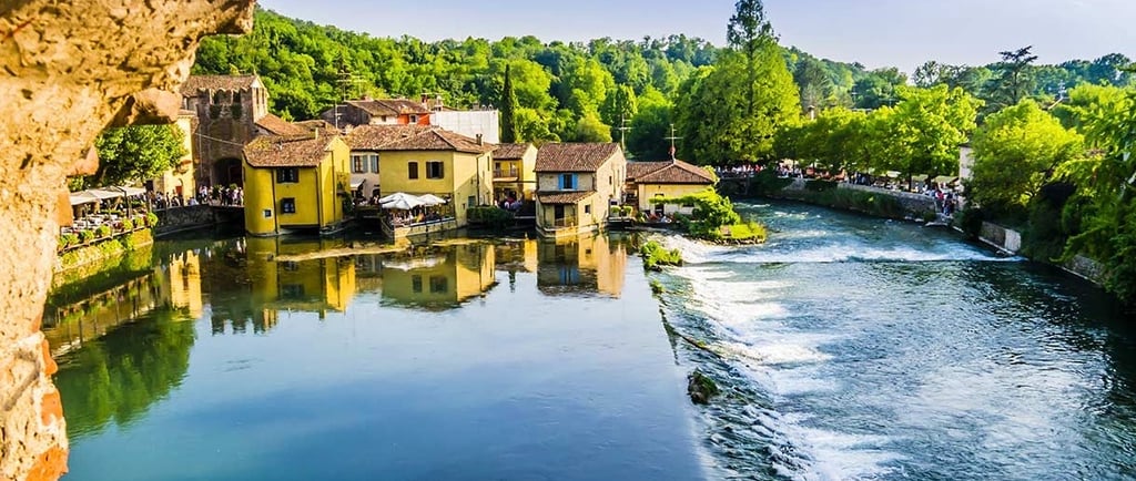 Punto di vista panoramico di borghetto con varie case e fiume e alberi attorno