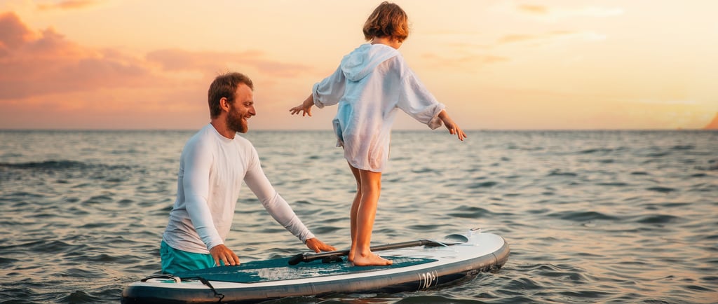 Tėtis laiko irklentę, ant kurios stovi vaikas ir bando išlaikyti pusiausvyrą.