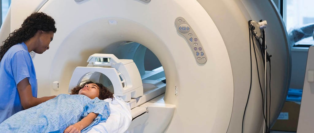 patient going inside an MRI machine with technician attending to the patient