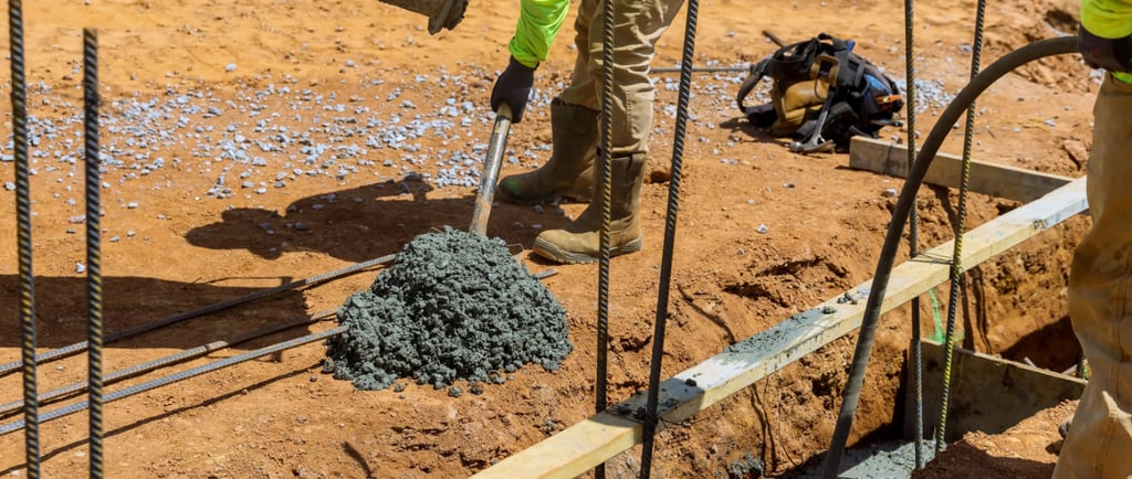 a man in a yellow jacket is pouring concrete into a concrete slab