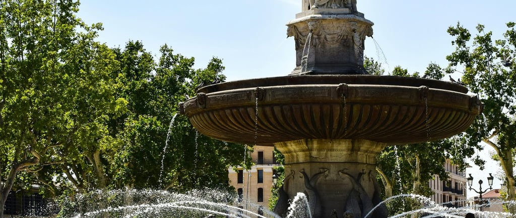 The historic Fontaine de la Rotonde in Aix-en-Provence featuring stone statues and water jets.