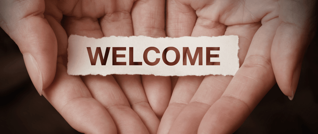 hands holding a piece of paper with the word welcome