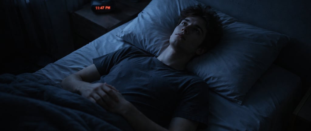 Jeune homme allongé dans le noir fixant le plafond, symbole de la nuit noire de l'âme