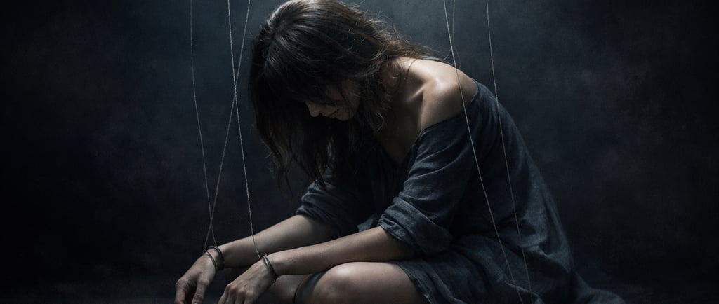 Femme assise dans l'obscurité avec des fils symbolisant la manipulation psychologique et l'emprise