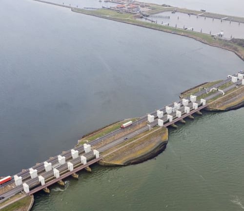afsluitdijk - a train traveling over a bridge over a river