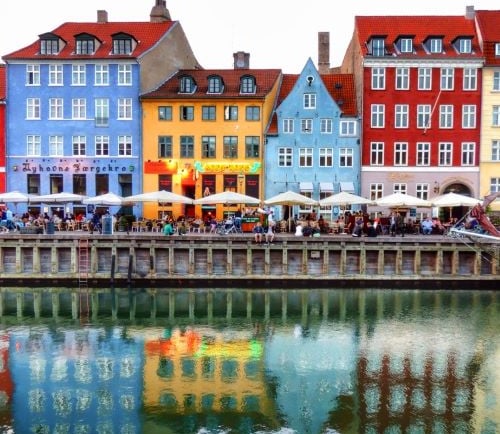a group of people sitting at tables near a body of water