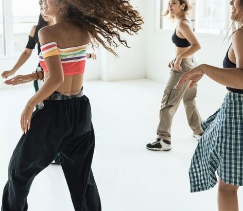 Diverse group of young women practicing hip hop dance moves in a bright, modern studio.