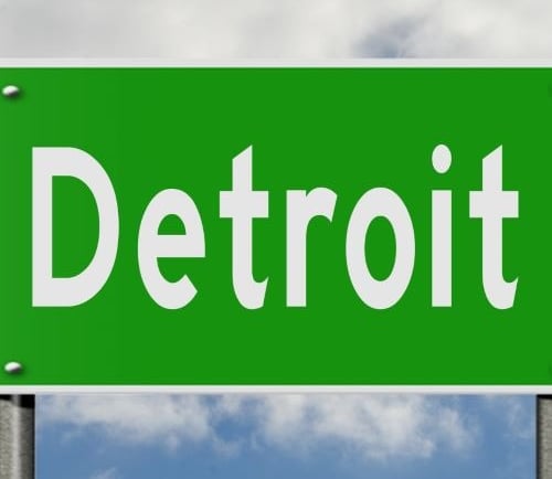 a green street sign with the word detroit