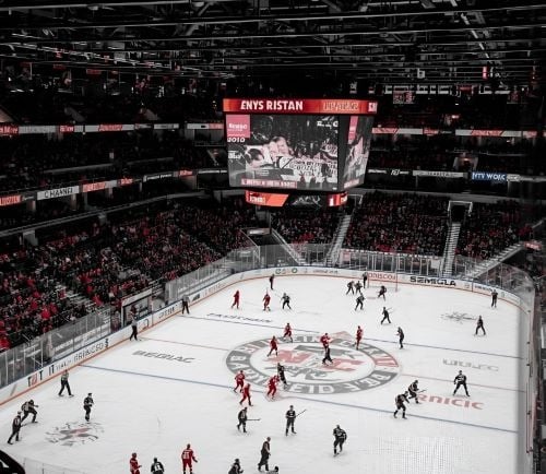 a hockey game in a stadium with a large screen