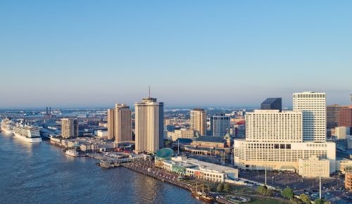 new orleans city skyline with a river and a bridge