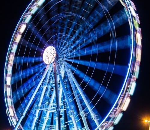 a ferris wheel with a ferris wheel in the middle of a dark night