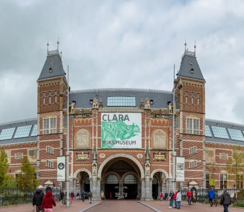 The Rijksmuseum in Amsterdam featuring the Clara the rhinoceros exhibition banner on its facade.