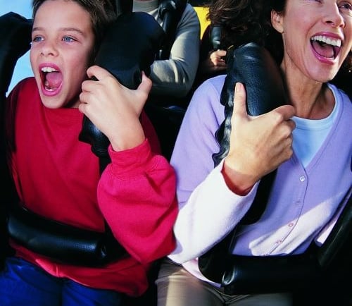 a woman and a boy are riding on a roller coaster
