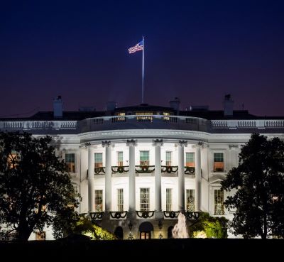 the white house at night with the american flag flying in the sky