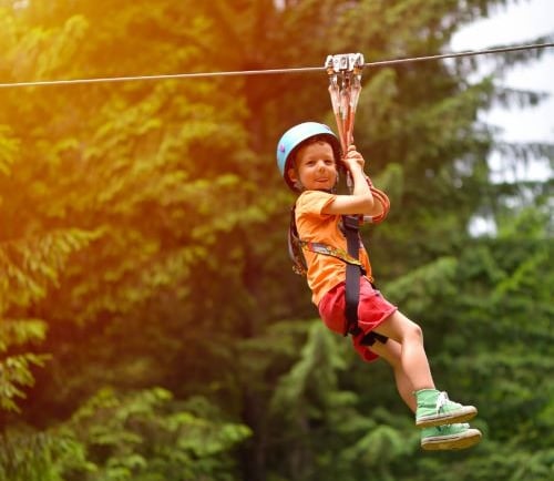 a young boy is zipping through the zip line of a zip line