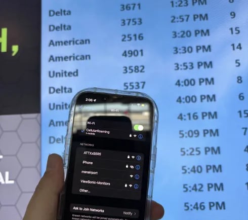 a person holding a cell phone in front of a screen
