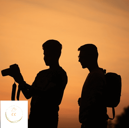 2 silhouettes d'amis, un homme tient un appareil photo