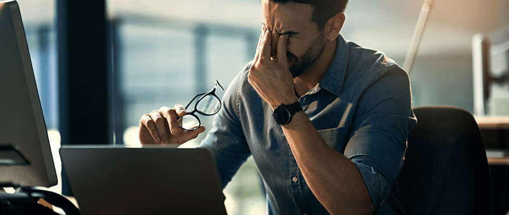 a man sitting at a desk with a laptop and glasses