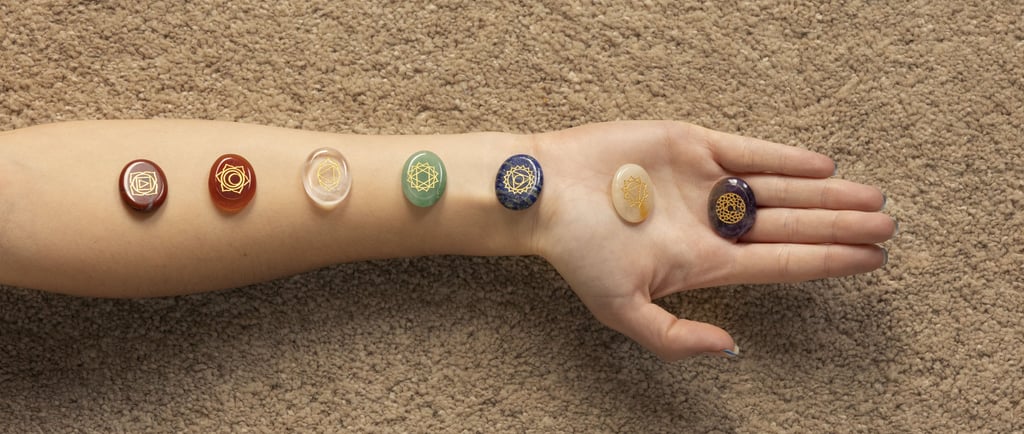 Bras allongé avec pierres de chakras alignées pour un soin énergétique et un rééquilibrage énergétiq