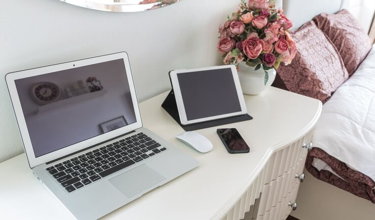 TechAid spec laptop computer sitting on a desk with a vase of flowers