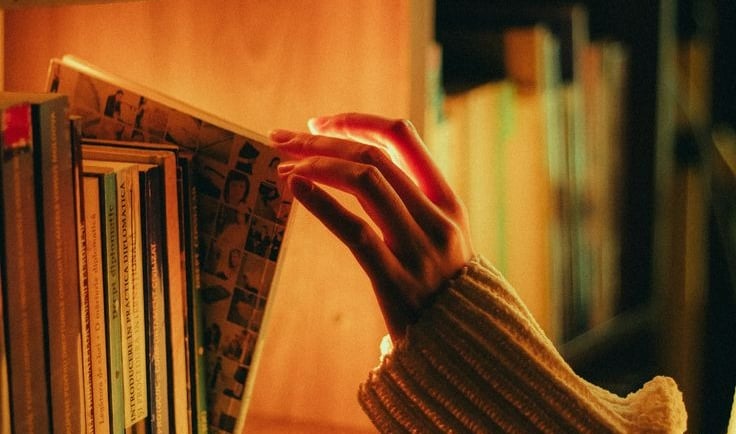 Cinematic image of a female hand taking a book out of the shelf