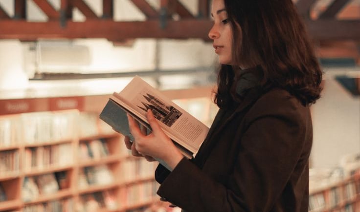 Photo of an elegant woman reading a book in a bookstore