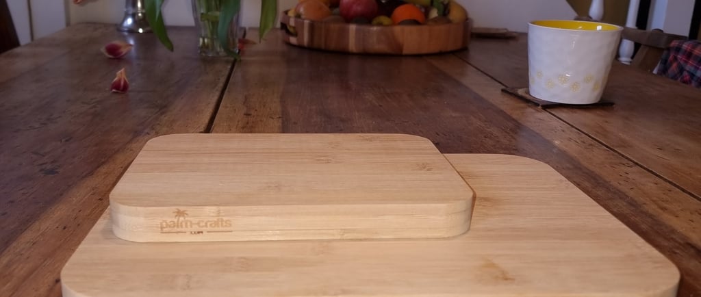 one 8" x 6" bamboo cutting board sat on top of a 12" x 9" bamboo cutting board with Palm-Crafts logos, on a table.